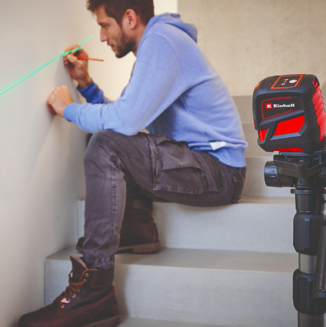 Krížový laser Einhell TCLL2G Remeselník označuje linku na stene pomocou zelenej projekcie krížového lasera Einhell TCLL2G