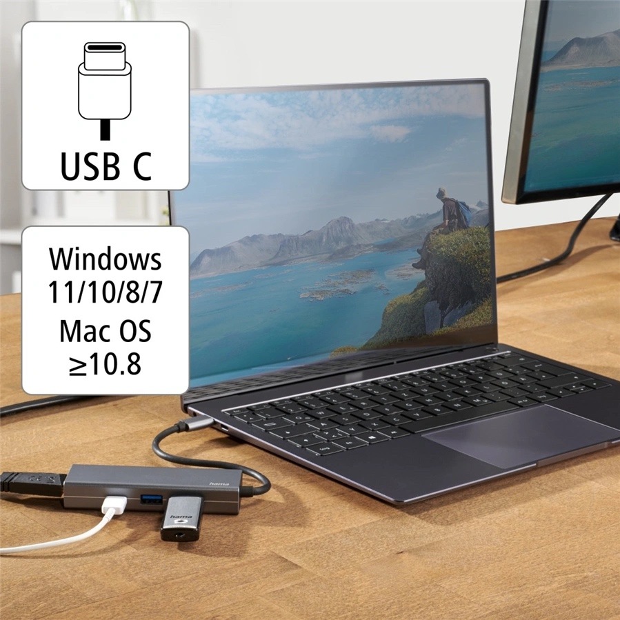 USB Hub Hama Multiport sivý Na obrázku je USB-C hub Hama použitý v praxi s notebookom na drevenom stole. Hub leží vedľa počítača, je do neho zapojený kábel a ďalšie zariadenia, a krátkym káblom je pripojený k notebooku. Vľavo sú informačné ikonky s nápisom USB C a zoznamom podporovaných systémov Windows 11/10/8/7 a Mac OS od verzie 10.8. Fotka ukazuje bežné použitie hubu na rozšírenie portov notebooku.