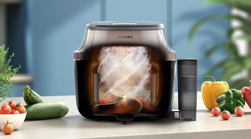 Fritéza teplovzdušná Philips Airfryer 5000 series 7,2 l, NA547/07 čierna Teplovzdušná fritéza Philips NA547/07 s grafickým znázornením prúdenia horúceho vzduchu a pary vo vnútri počas prípravy. Vedľa spotrebiča je umiestnená nádoba na vodu a na kuchynskej linke sú čerstvé suroviny, ako cuketa, papriky a paradajky.