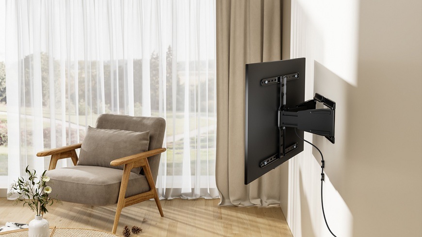 Držiak na TV GoGEN slim, polohovatelný XL čierny Zadný pohľad na polohovateľný SLIM držiak na TV GoGEN v interiéri – ukážka vedenia kábla pozdĺž ramena a natočenie obrazovky smerom ku kreslu