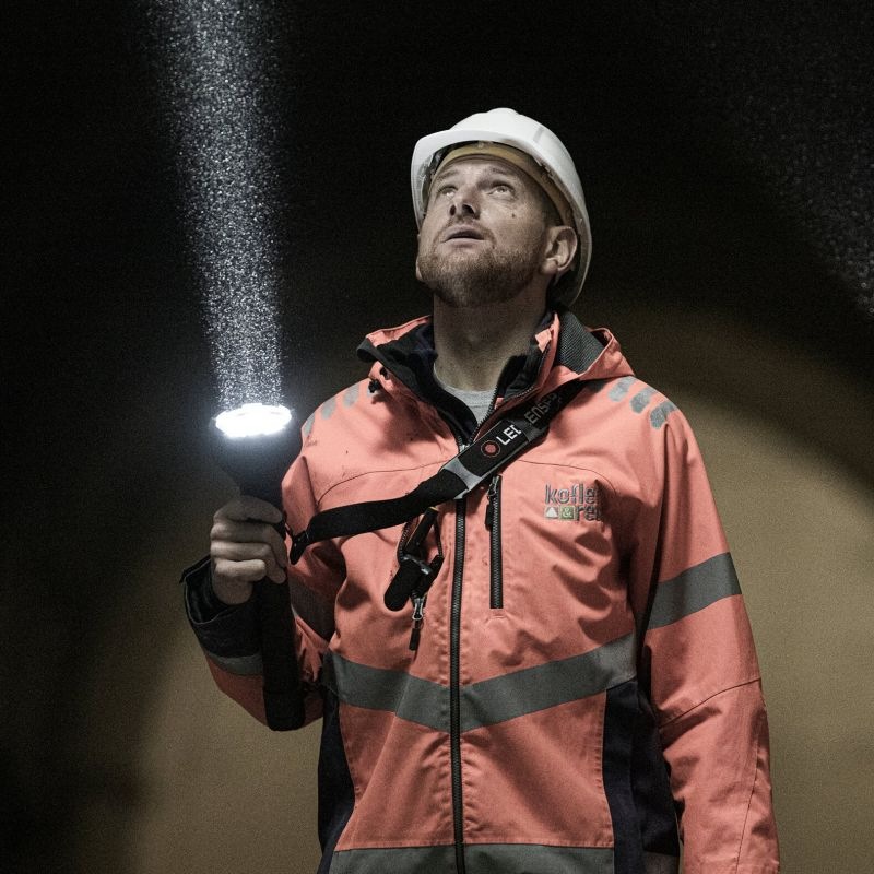 Muž s rozsvieteným svietidlom LEDLENSER P21R vzhliada k miestu, na ktoré dopadá silný lúč
