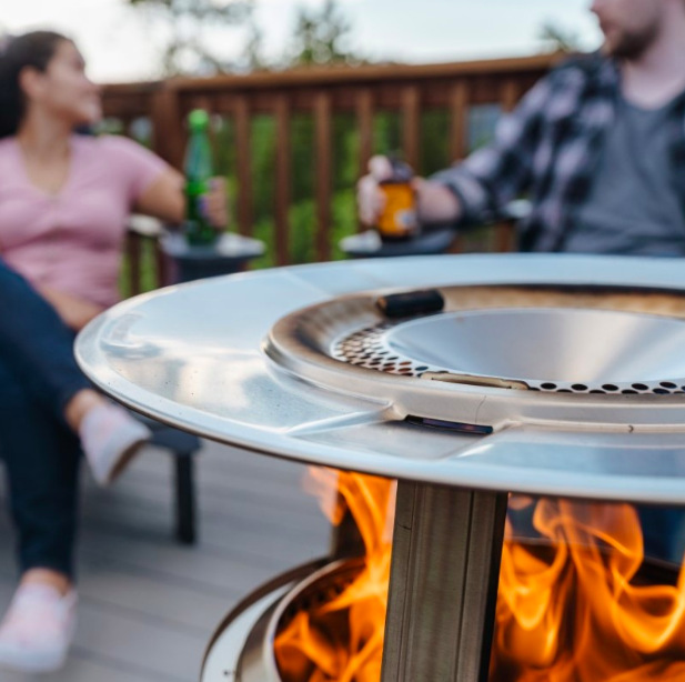 Detail nerezového rozptylového disku deflektora Solo Stove Ranger nad plameňmi ohňa