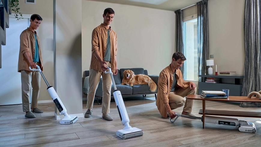 Tyčový vysávač Hoover HW400 011 biely muž používa vysávač Hoover HW400 011 na rôznych miestach v obývačke