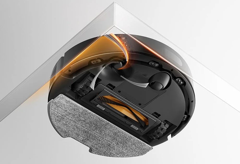 Robotický vysávač Dreame F20 biely Pohľad na Dreame F20, ktorý v rohu miestnosti predĺženými štetinami vymetáva prach.