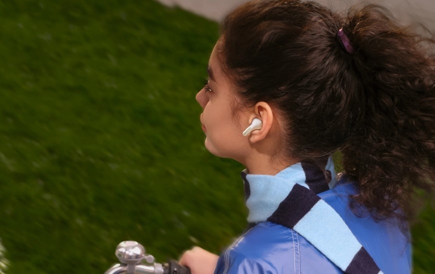 Slúchadlá Xiaomi REDMI Buds 8 zelená Žena idúca na bicykli má v ušiach slúchadlá Xiaomi REDMI Buds 8 s potlačením šumu v mikrofónoch