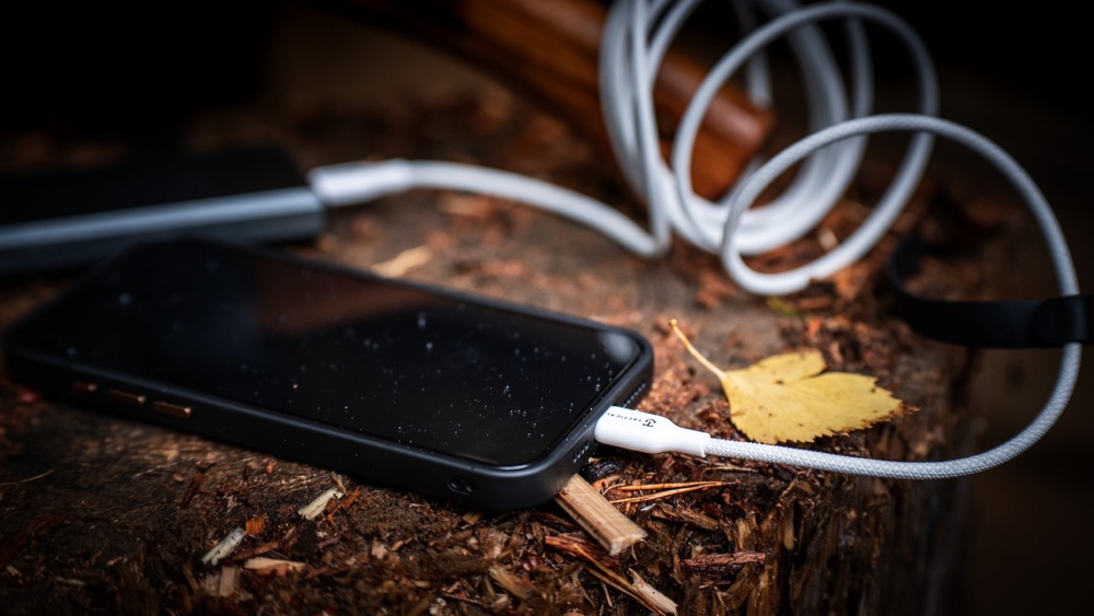 Smartphone položený v prírode napojený na powerbanku cez kábel Tactical Stitch Thread