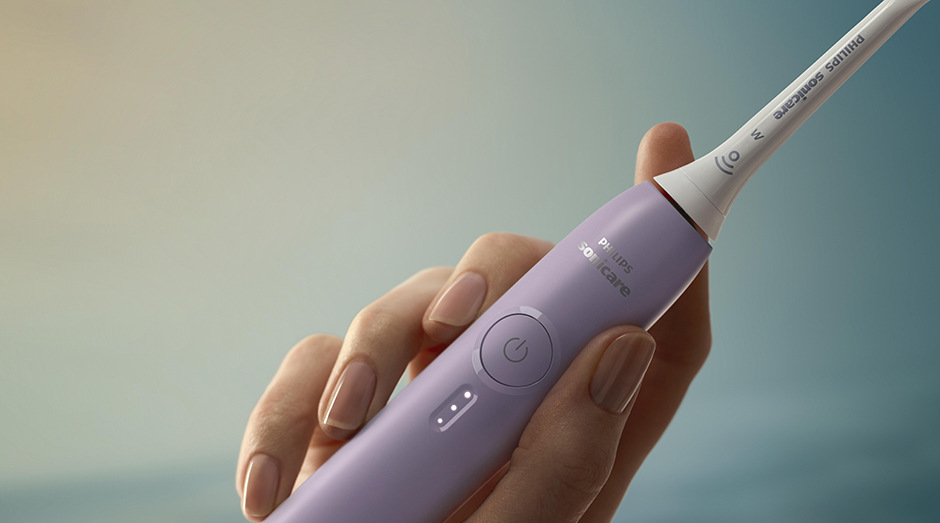Zubná kefka Philips Sonicare 3100 HX4033/27 fialová Detail kefky Philips HX4033/27 Sonicare 3100 v ženskej ruke