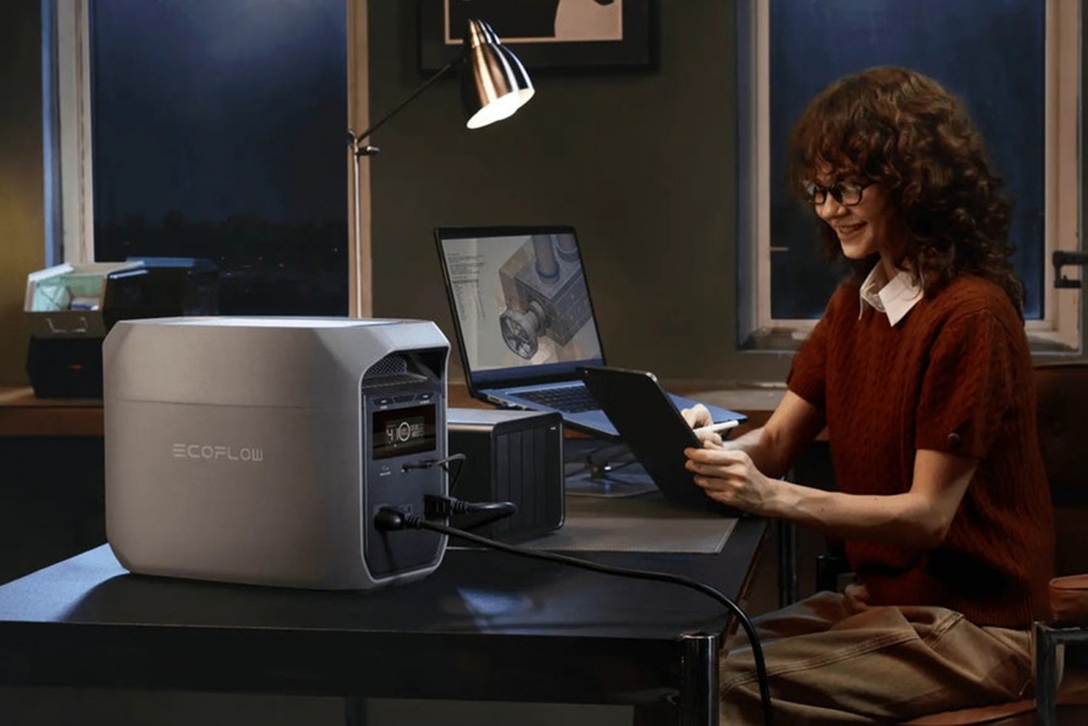 Nabíjacia stanica EcoFlow DELTA 3 Classic (1024 Wh) sivá Žena pracujúca v noci pri stole s notebookom napájaným zo stanice EcoFlow DELTA 2.