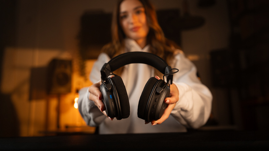 Headset ENDORFY VIRO Infra Wireless čierny Žena držiaca headset ENDORFY VIRO Infra Wireless s viditeľnými ovládacími prvkami a konektormi