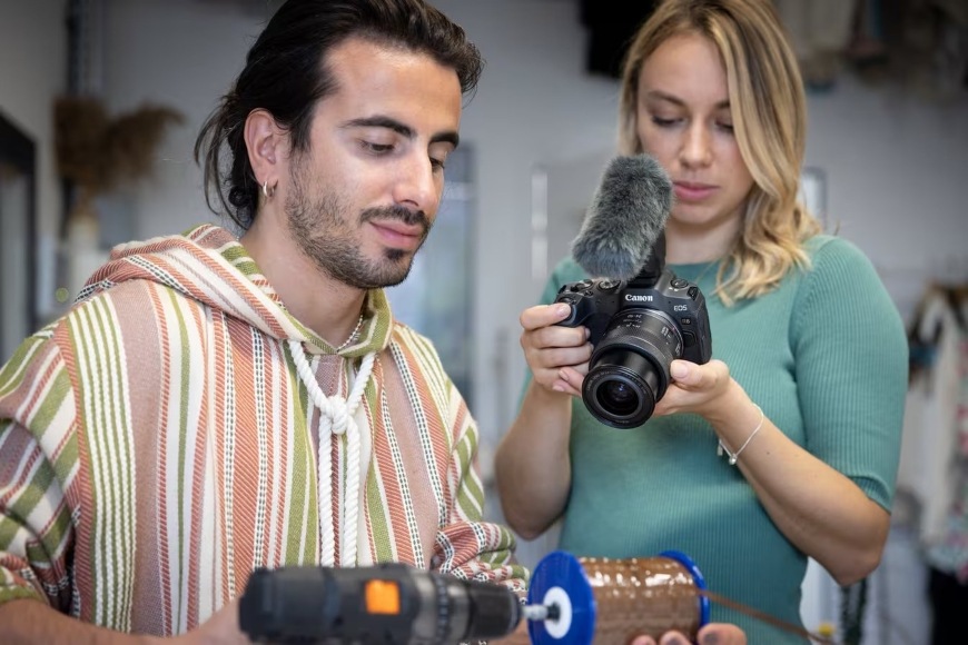Žena natáčajúca video pracujúceho muža s bezzrkadlovkou Canon EOS R8