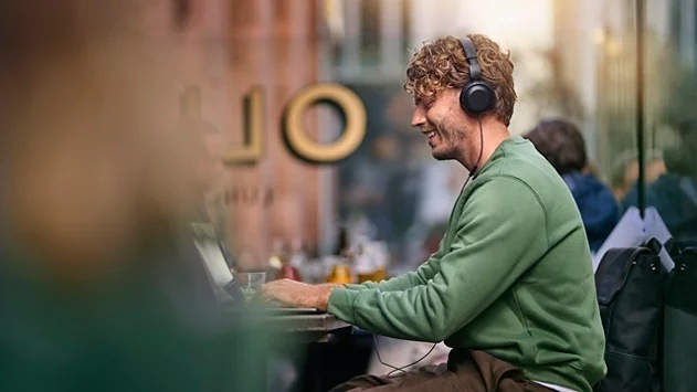 Slúchadlá Philips TAH2100BK/00 čierna Smejúci sa muž pracujúci na notebooku má na hlave slúchadlá Philips