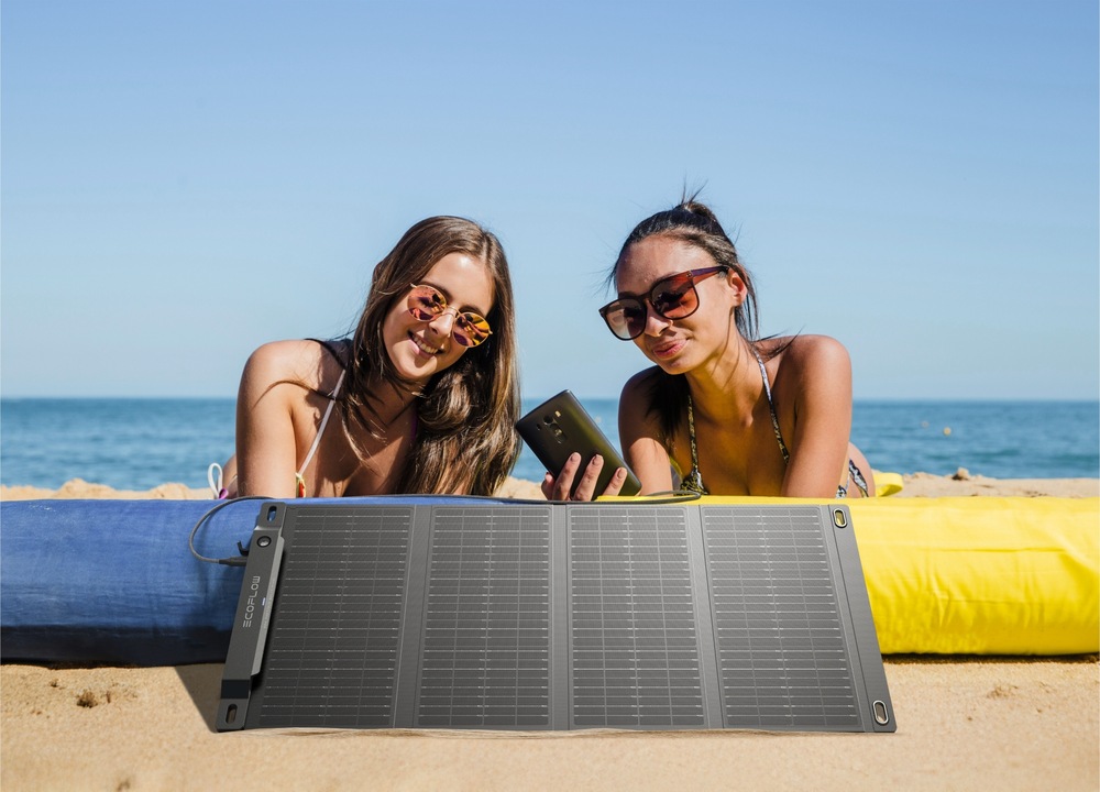 Dve dievčatá na pláži s panelom EcoFlow a mobilom v ruke