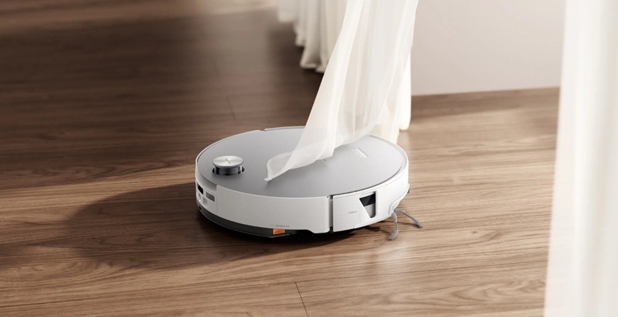Detail obrázku robotického vysávača v okolí záclon.