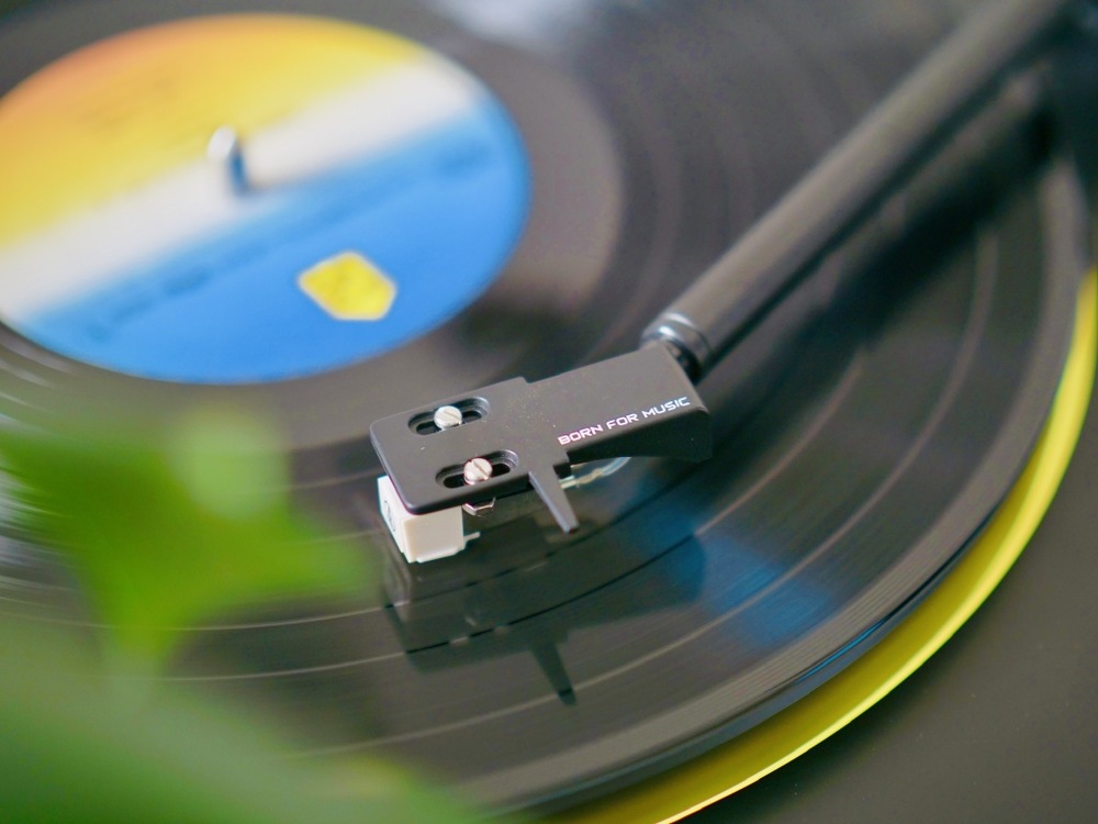 Detailný záber na ihlu prenosky dosadajúci na vinylovú dosku pri prehrávaní.